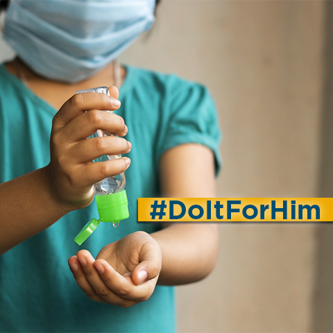 A child uses hand sanitizer and a facial covering.