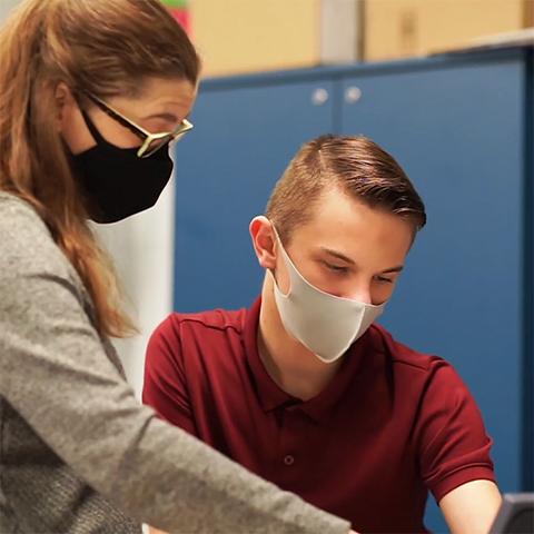 A teacher helps a student.